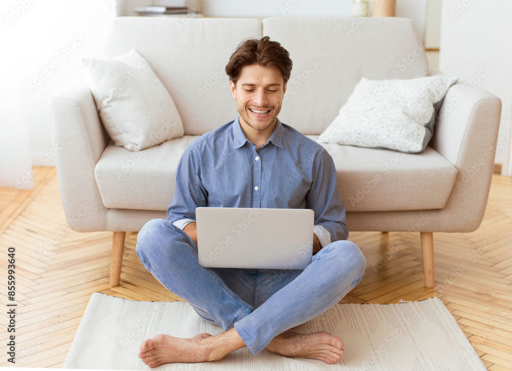 Aufkleber a man is sitting on the floor in a living room, using a laptop. he is smiling and appears to be rela