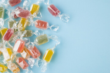 Assorted wrapped up jelly candies on blue background, top view.