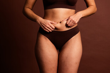 Cropped photo of plus size pretty lady underwear doing tummy massage isolated brown color background