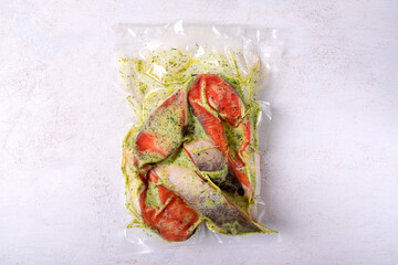 Vacuum packed pink salmon pieces in creamy sauce with herbs ready for roasting. Red fish steaks in vacuum package