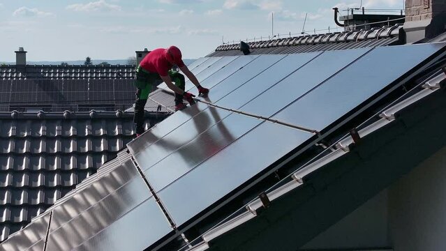 Worker Installing Roof Solar Panels on a Sunny Day