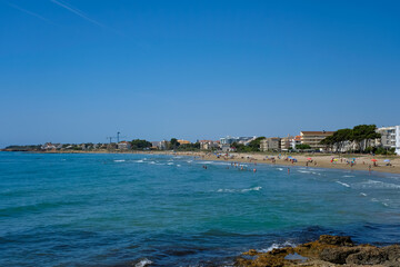 People in the distance on the beach. Seaside village Alcossebre, Castellon, Spain. Panorama.  Popular tourist destination.