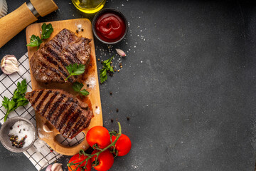 Grilled beef steak on wooden cutting board with ketchup sauce and condiments, top view copy space