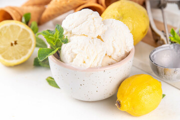 Sour sweet lemon sorbet ice cream, refreshing tasty lemon gelato dessert with fresh lemons, mint and waffle ice cream cones, white table background copy space