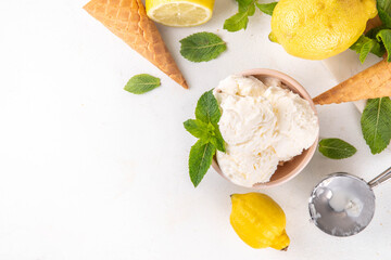 Sour sweet lemon sorbet ice cream, refreshing tasty lemon gelato dessert with fresh lemons, mint and waffle ice cream cones, white table background copy space