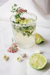 sweet fresh cocktail with flowers and cut lime on stone desk background