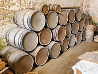 A pile of brown wooden barrels against the wall