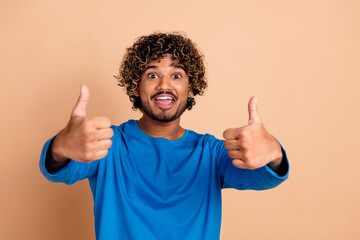 Photo of glad nice positive guy wear trendy blue clothes thumb up isolated on beige color background