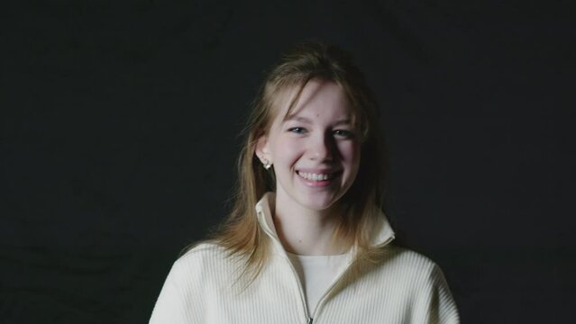 The girl laughs on a black background. Close-up