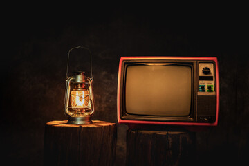 Antique oil lamp and old TV in a dark room at night on black tree stump on black in studio, Vintage lantern with television, kerosene lamp