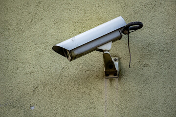 Security Camera Mounted on a Green Wall monitoring state surveillance security concept