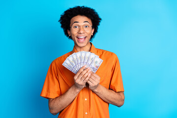 Photo of handsome good mood guy wear orange shirt spectacles holding cash fan emtpy space isolated...