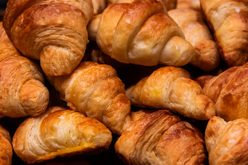 Cloes-up many fresh baked croissants piled on a tray. Food background.