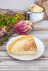 
traditional South African milk tart and protea flowers with fynbos, on a weathered rustic whitewashed wood. Lots of copy space