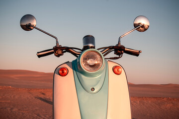 Retro blue scooter at sunset in the golden sand of the Namib Desert