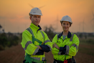 Team Engineers men and woman checking and inspecting on construction with sunset sky. people operation. Wind turbine for electrical of clean energy and environment. Industrial of sustainable.