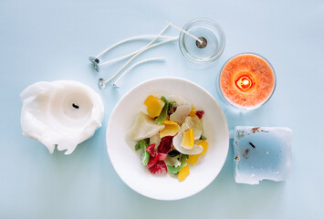 Reusing old candles leftovers and making melting a new one: various ingredients on table: candle wicks, glass jar, old candles wax. Above view with light blue background, studio shot.
