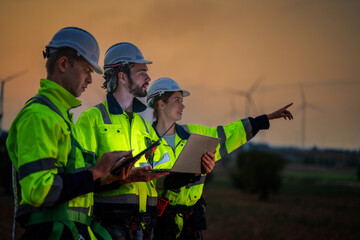 Team Engineers men and woman checking and inspecting on construction with sunset sky. people operation. Wind turbine for electrical of clean energy and environment. Industrial of sustainable.