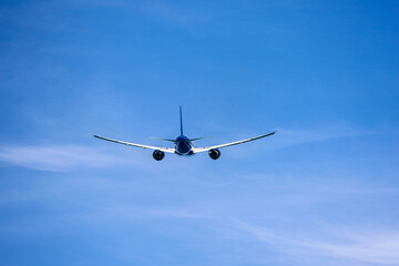 Airplane flying in blue sky, rear view. Passenger plane at flight, travel concept