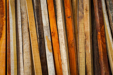 Various planks of lumber in different shades and textures are neatly stacked together, showcasing a range of natural wood colors and grains.