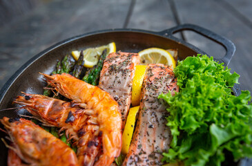 Healthy baked salmon steaks with greens and asparagus in a black cast iron skillet. A delicious low-carb breakfast.