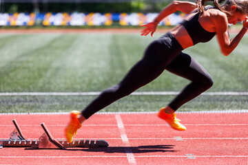 Female sprinter launches from the starting blocks with explosive power