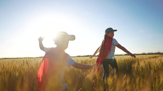 A group of kids playing a video game of superheroe together. Child hero fun concept. Superhero running through the wheat with children. A group of kids playing sunset a game of running together.