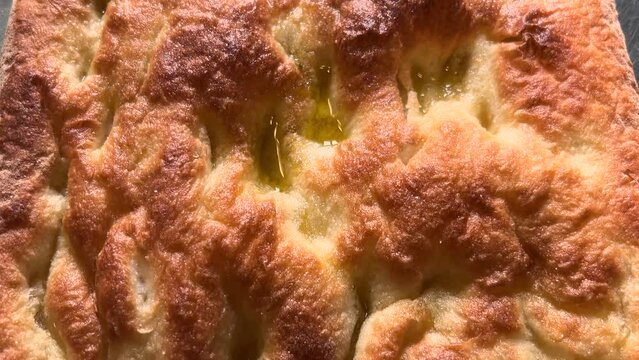 Focaccia with extra virgin olive oil, typical flat bread of Genoa, slide shot in top view