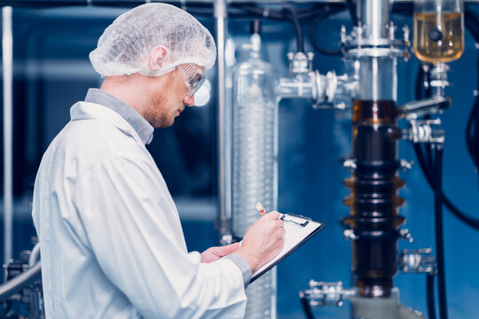 Scientist Medical Factory Staff Working in Science Lab. Medicine factory Technician Employee Check Care Products Quality in Sterilize Room Taking Note in Check list.