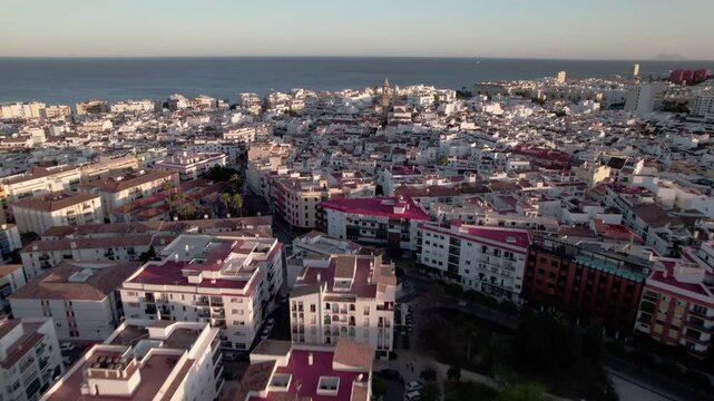 Enjoy a breathtaking aerial view of a Mediterranean coastal cityscape during a beautiful sunset