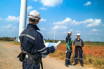 A team of engineers is inspecting the construction of wind turbines and surrounding structures in...