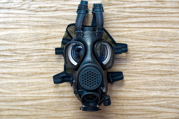 Close-up of Swiss Army black gas mask lying on oak parquet floor. Photo taken June 19th, 2024, Zurich, Switzerland.