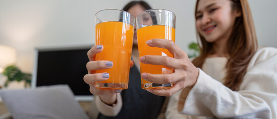 Lesbian Couple Enjoying Healthy Orange Juice at Home in a Modern Living Room Setting