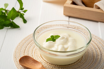 Low calorie yogurt in glass bowl on white wood background
