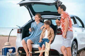 Family vacation trip traveling by the beach with electric car, happy family recharge EV car,...