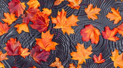 Bright orange and red autumn leaves floating on rippling dark water, creating a striking contrast and dynamic composition. Ideal for seasonal designs.