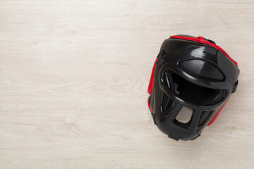 Black leather boxing helmet on wooden background, top view.