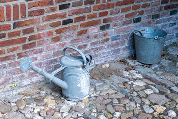 watering can and bucket on brick wall