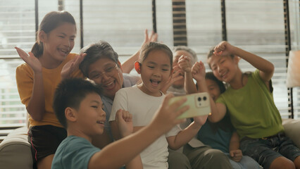 happy multi generation lifestyle concept asian grandparent and grand children taking selfie smartphone together on sofa in living room daylight at home smiling cheerful asian family visit grand parent