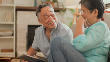 old asian senior couple packing cloth and stuff for a trip together,happiness asian old age retired mature adult enjoy arrange cloth together on floor at living room at home interior background