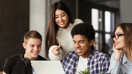 College students using laptop in library, studying together for school assignment