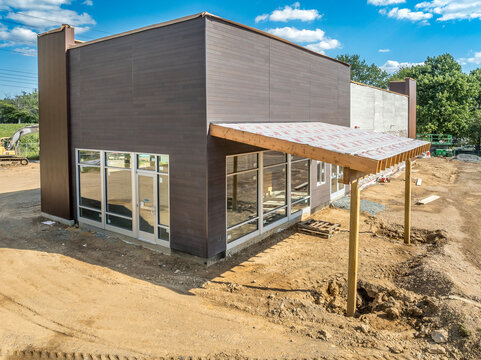 American commercial real estate fast food restaurant building during construction with shade structure entrance, partially installed stone veneer blue sky background