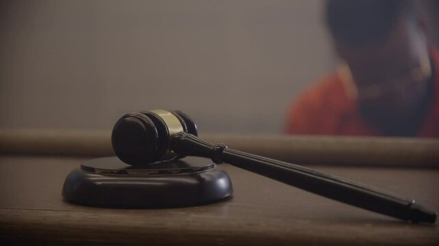 Rack focus from black inmate to gavel in court room