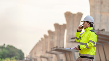 An Asian male engineer works at a motorway bridge construction site,Civil worker inspecting work on crossing construction,Supervisor working at high-speed railway construction site