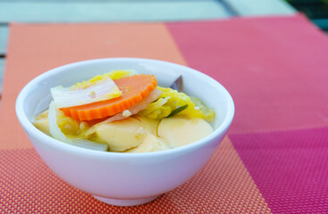 Closeup of Tofu Vegan Soup with carrots, cabbage and celery in a white bowl. Healthy food in the moring.