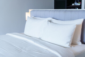 Closeup of new bed comforter with white pillows, headboard in bedroom of hotel.