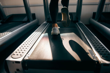 A female runner running on a treadmill, close-up of shoes.