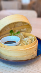 Chinese Steamed Buns and dumplings in a bamboo steamer with soya sauce