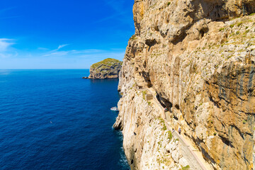 Impresionante vista de los acantilados que conducen a la Cueva de Neptuno en Cabo Caccia, Cerdeña, Italia. La escalinata tallada en la roca serpentea a lo largo de la pared del acantilado.