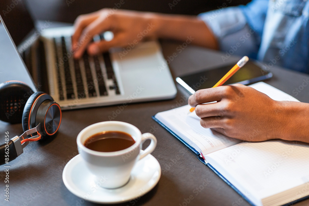 Aufkleber high angle view of person is seated at a desk, typing on a laptop while sipping from a cup of coffee